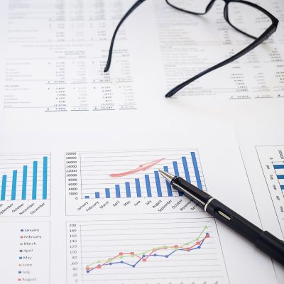 A sheet of financial planning data and charts with a pair of glasses and a pen resting on top.