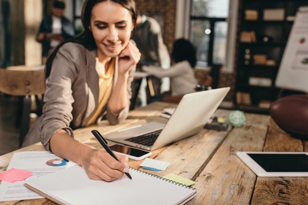 Business owner reviewing financial reports at desk with laptop and notes