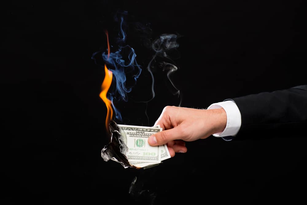 Burning cash in hand representing financial loss from incorrect loan balances in QuickBooks Online