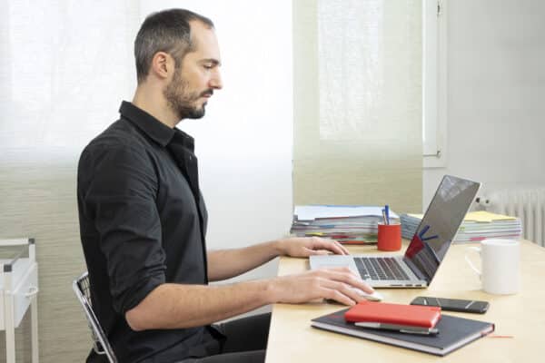 Business owner responding to a monthly bookkeeping question by email on a laptop