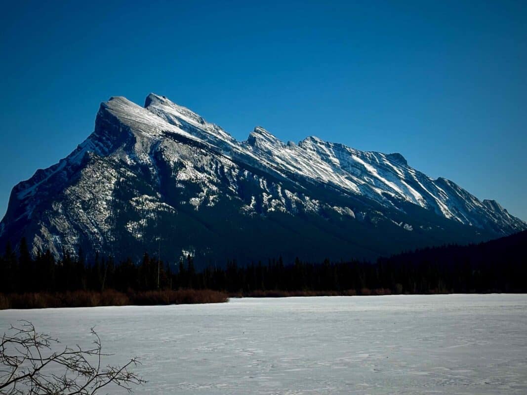 Snow-covered mountain range under a clear blue sky overlooking a frozen lake, representing clarity and perspective in business finances