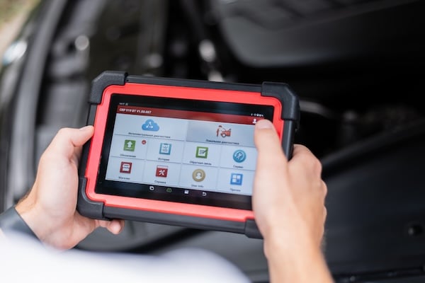 Technician using a diagnostic scan tool to identify hidden vehicle problems before repairs, representing a business financial diagnostic review