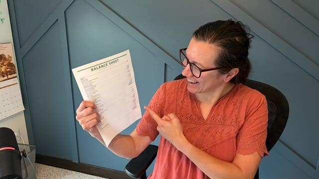 Amber Malone reviewing a printed balance sheet from QuickBooks