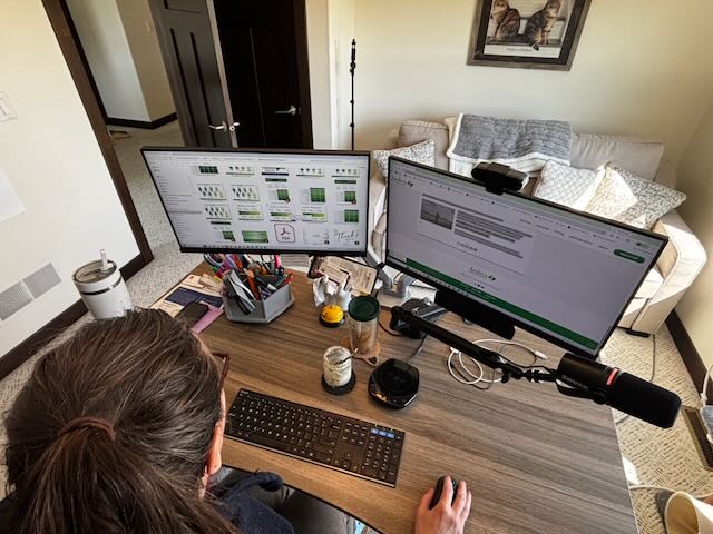 Bookkeeper at a dual-monitor desk reviewing financial metrics and reports for a service business
